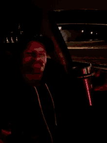 a person is holding a red object in their hand in a dark room