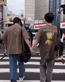 two people crossing a street with one wearing a shirt that says aemé de la vie