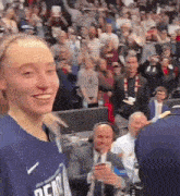 a woman in a denver jersey is smiling in front of a crowd .