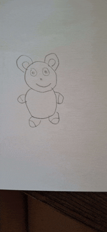 a child 's drawing of a teddy bear is sitting on a piece of paper .