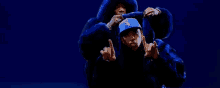 a couple of men in blue fur coats are dancing on a blue background .