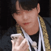 a young man wearing a medal around his neck is looking at his phone .