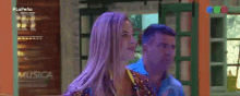 a woman with purple hair is standing next to a man in front of a sign that says la pena