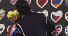 a man is standing in front of a wall of hearts with one that says belgium
