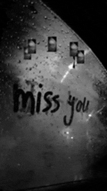 a black and white photo of a car windshield with the words miss you written on it