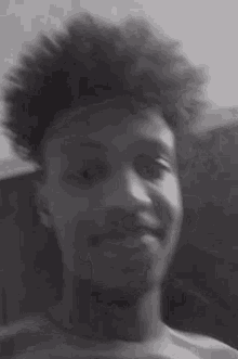 a black and white photo of a man with curly hair smiling .