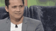 a man in a suit and white shirt is sitting on a couch .