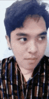 a close up of a man 's face with a plaid shirt