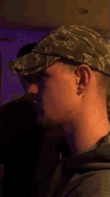a man wearing a camo hat looks to his right