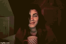 a woman is drinking from a cup with a red handle .