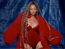a woman with braids is wearing a red bodysuit and a red coat