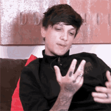 a young man with a tattoo on his arm is sitting on a couch making a funny face .