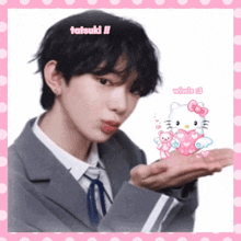 a man in a suit and tie is holding a hello kitty heart in his hand .