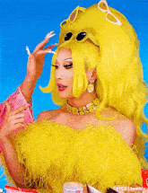 a woman in a yellow feathered top is getting her makeup done by tayce