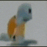 a toy turtle with an orange shell on its back is sitting on a white surface .