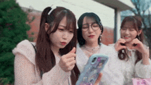 three young girls are looking at a cell phone together