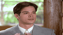 a man in a suit and tie is holding a pink flower