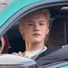 a man with blonde hair is sitting in a car