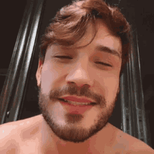a man with a beard is smiling with his eyes closed and his mouth open .
