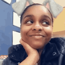 a woman wearing a cat ear filter is smiling and looking at the camera .