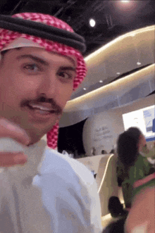 a man wearing a keffiyeh and a white shirt takes a selfie