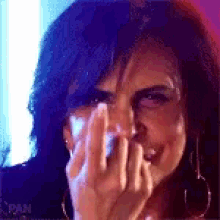 a woman is covering her face with her hand and making a face .