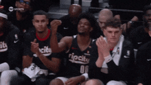a group of basketball players are sitting in the stands and one of them is wearing a ripcity jersey