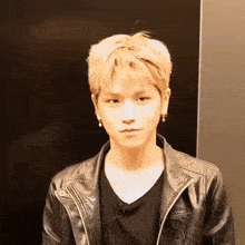 a young man wearing a black leather jacket and a black shirt