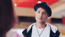 a man wearing a hat and a necklace is talking to a woman in a restaurant .