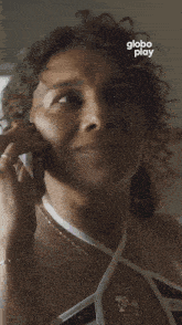 a woman is talking on a cell phone with globo play written in the corner