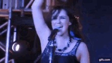 a woman singing into a microphone with her arms in the air .