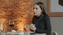 a woman sits at a table with a glass of wine and a plate of food