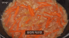 a blender is being used to mash carrots and onions in a pan .