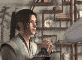 a man in a ponytail is standing in front of a bookshelf