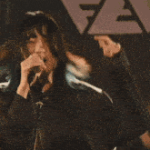 a woman is playing a guitar on a stage while a man plays drums .