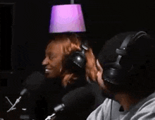 a man and a woman wearing headphones are talking into microphones in a dark room .