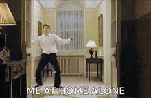 a man is dancing in a living room with the words `` me at home alone '' written on the bottom .