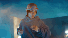 a man wearing a hat and a hoodie is pointing at something .