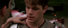 a man in chain mail is being touched by another man in armor .