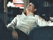a man in a white shirt is sitting in a chair with his mouth open