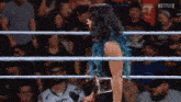 a woman with blue hair is standing in a wrestling ring with a netflix logo in the corner
