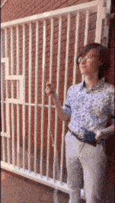 a woman with glasses is standing in front of a brick wall holding a cell phone .