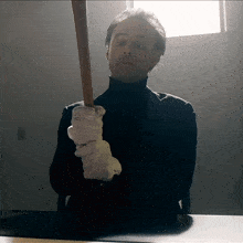 a man wearing white gloves is holding a wooden bat