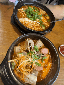 two bowls of food on a wooden table with a spoon