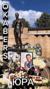a statue of a man is surrounded by flowers and a sign says okabers