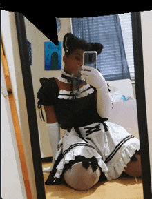 a girl in a maid costume taking a selfie in front of a mirror
