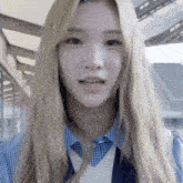 a woman with long blonde hair is wearing a blue and white shirt and a blue vest .