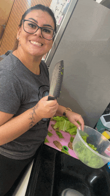 a woman with glasses is smiling while holding a knife