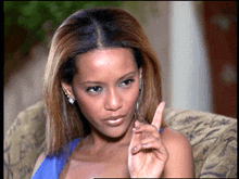 a woman in a blue dress is sitting in a chair with her finger up