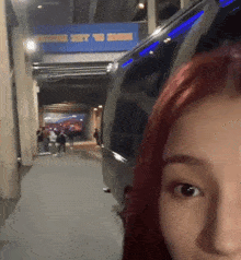 a woman with red hair is standing in front of a blue sign that says ' stadium '
